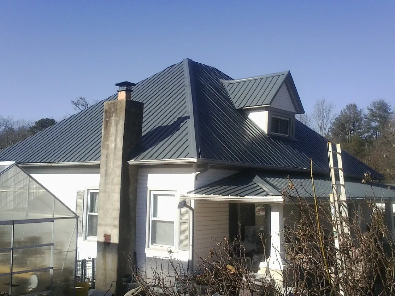 Dark blue standing seam metal roof on a white farmhouse with dormer — Slate & Tile Roof Repair by Roofing Brothers in Davisburg