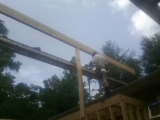 Carpenter setting a ridge beam over a new addition frame — Ice Dam Removal by Roofing Brothers in Davisburg
