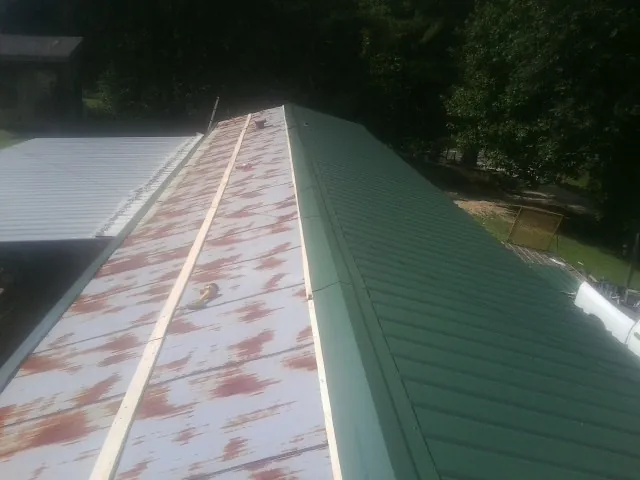 Old rusted panels beside newly installed green metal roofing — Wind Damage Roof Repair by Roofing Brothers in Davisburg