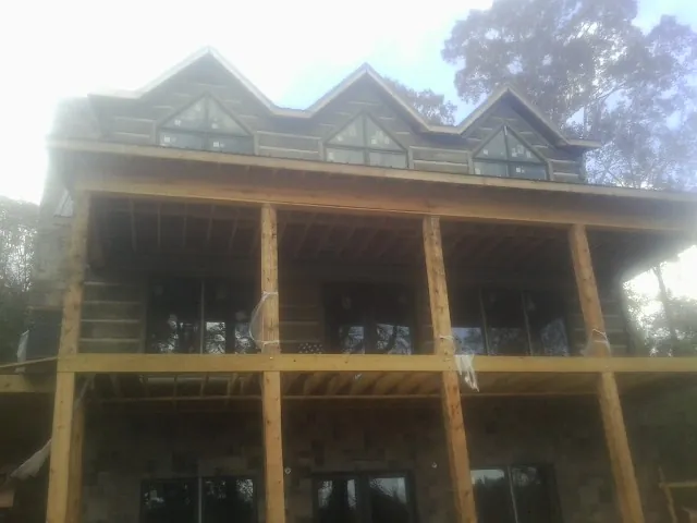 Dormers and porch framing on a large log home under construction — Roof Coating work by our crew in Davisburg