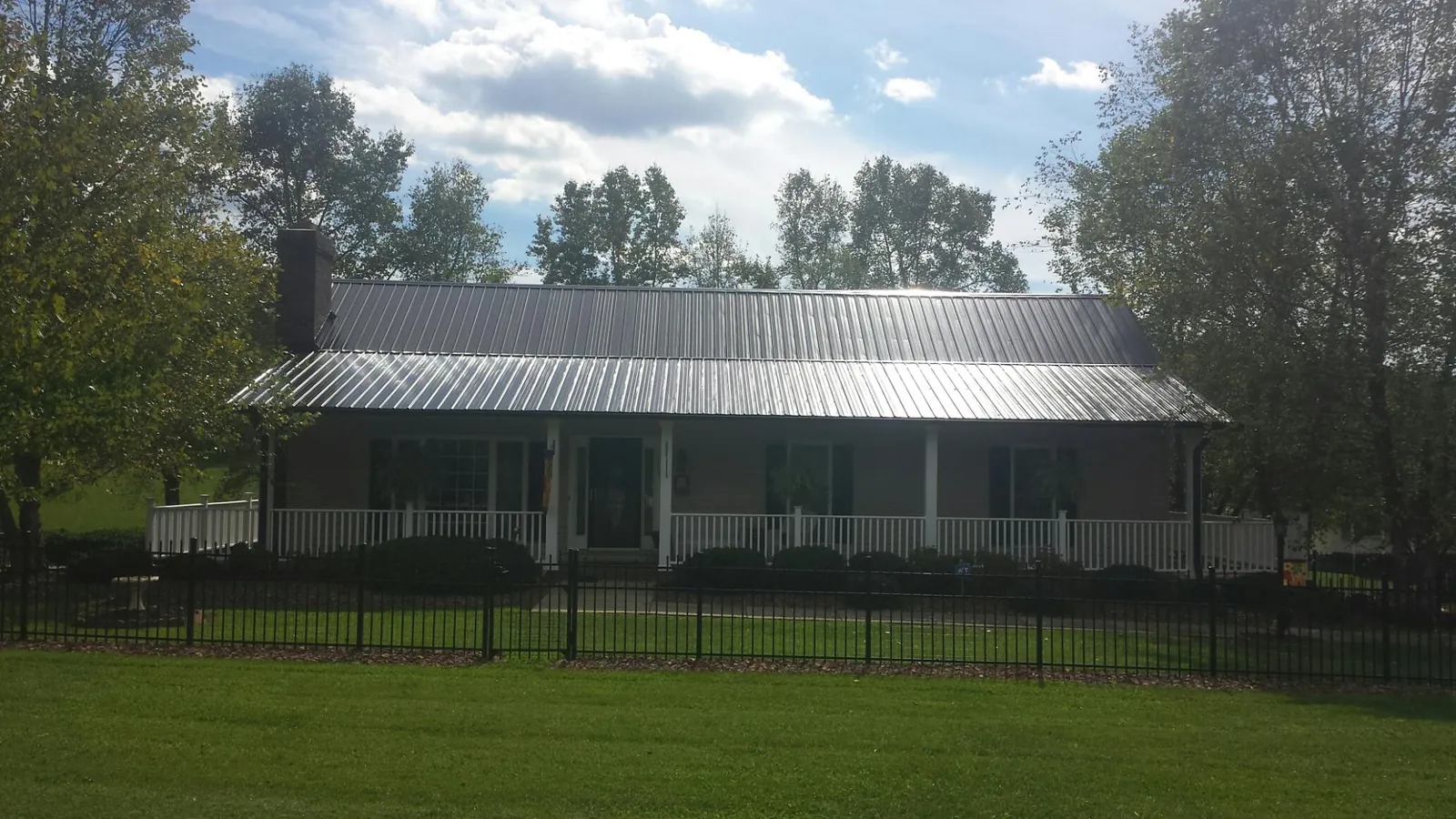 Gray metal roof on a brick ranch with a full width front porch — Gutter Guard Installation work by our crew in Davisburg