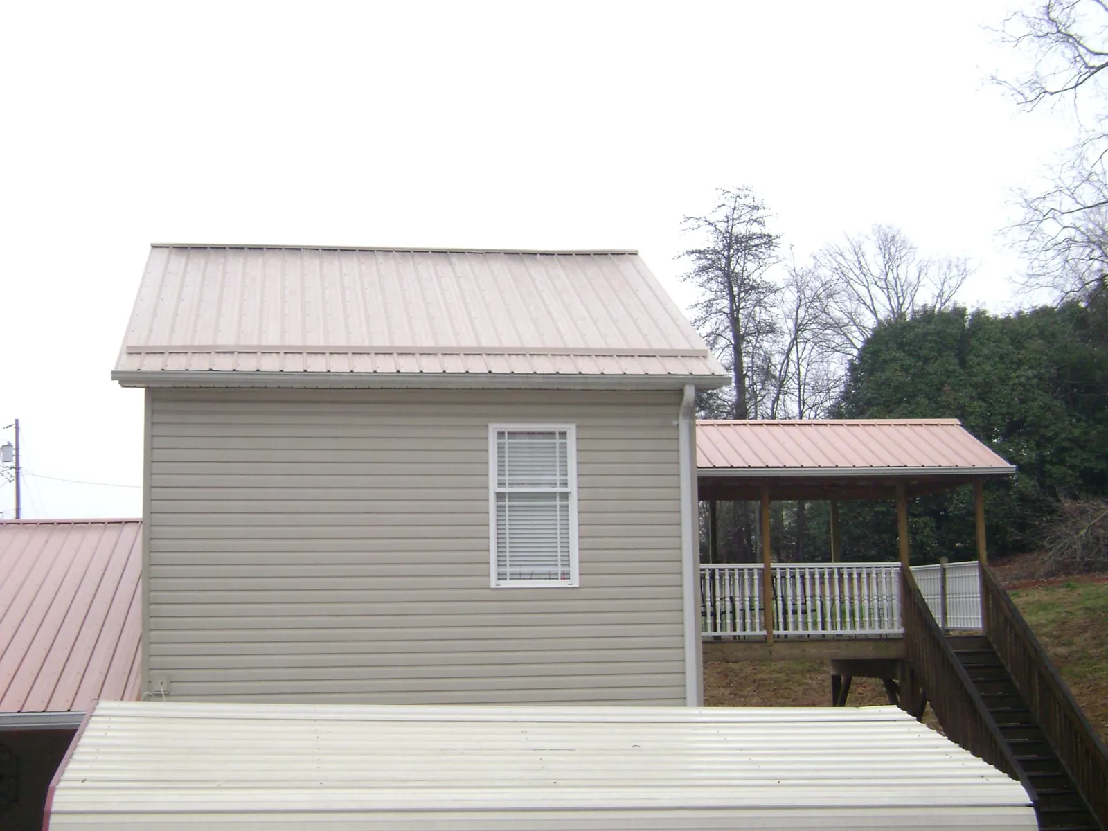 Tan metal roofs on a two story addition and attached porch, from a Roof Replacement job in Davisburg