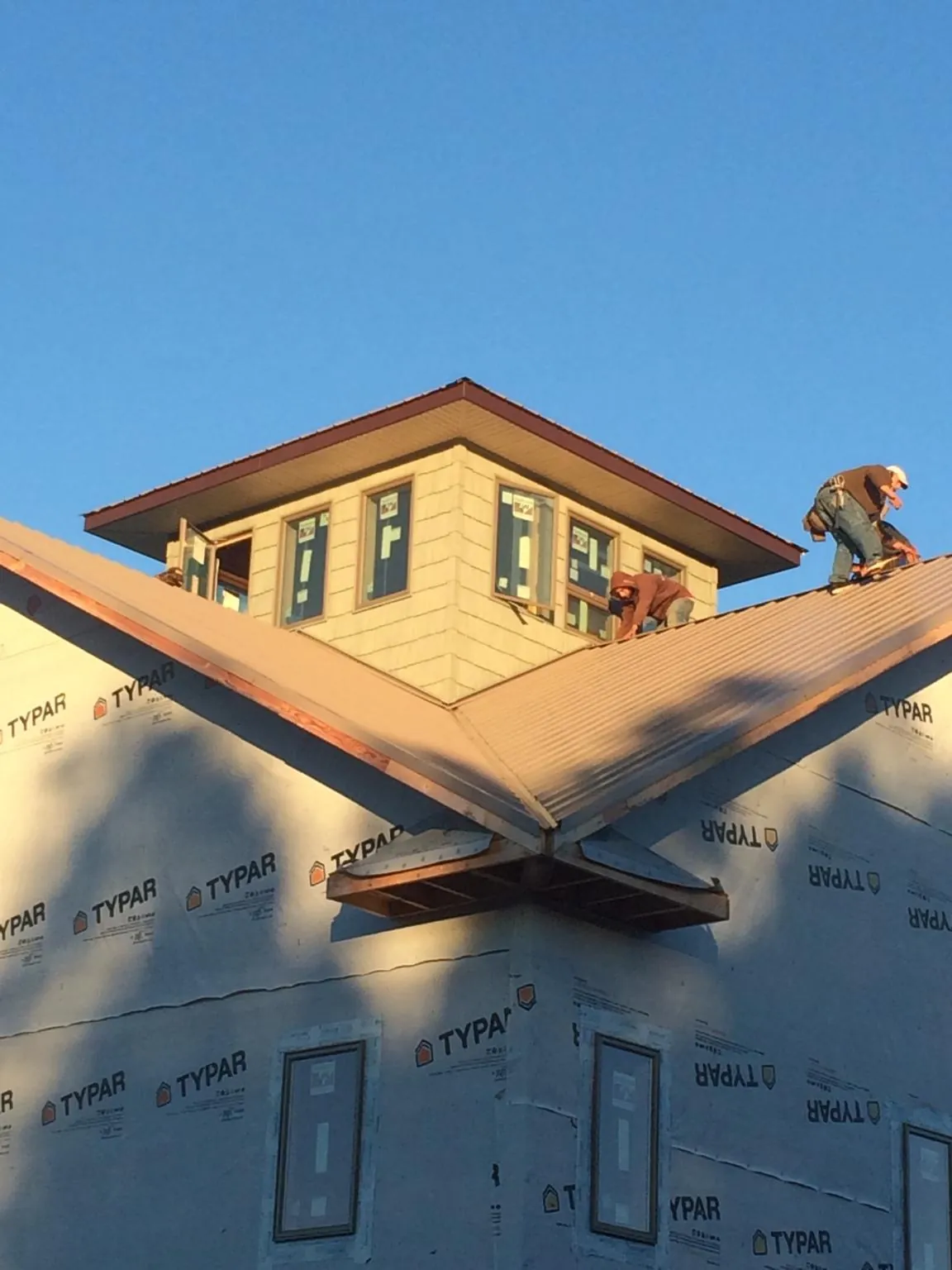 Roofers working around a rooftop cupola on a new metal roof at sunset — Roof Waterproofing in Davisburg by Roofing Brothers